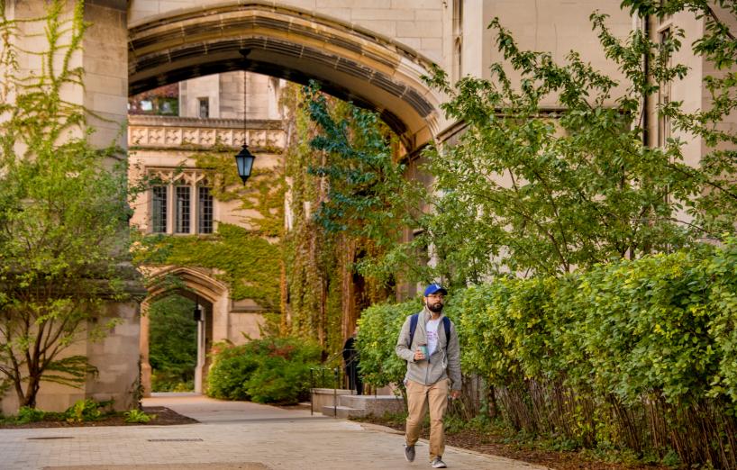 A student walks under an archway in the SSD Quad