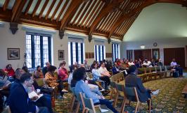 Symposium audience seated in a semi-circle listening and writing notes.