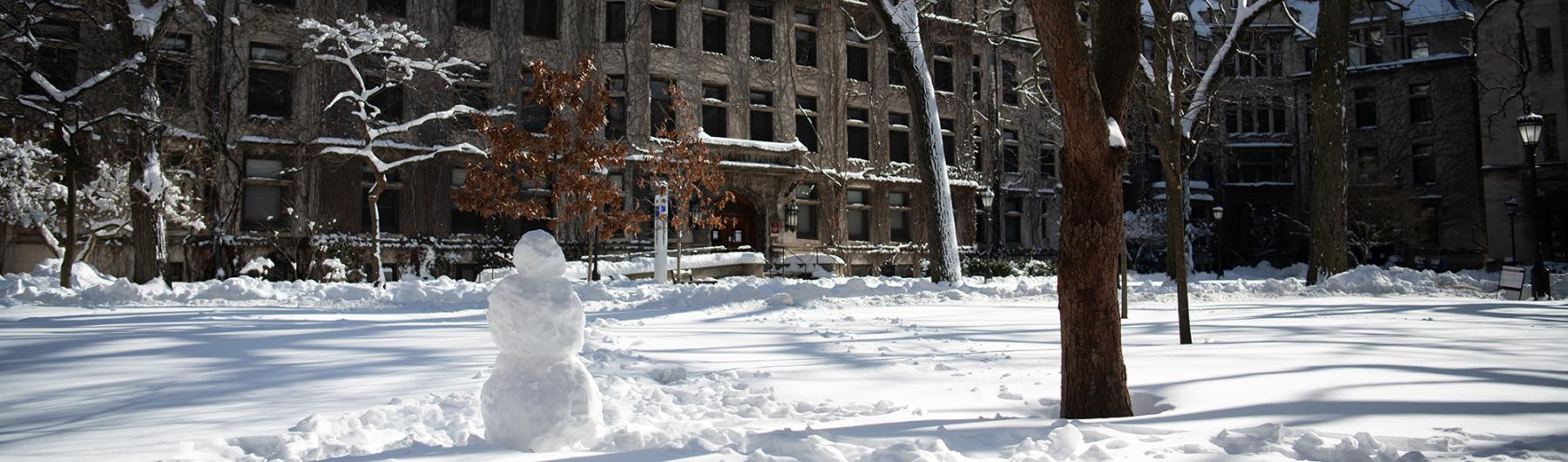 UChicago campus with snow on the ground and a snowman.