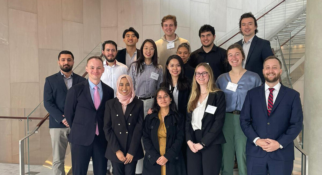 A group of students and faculty standing with an alumnus on a staircase.