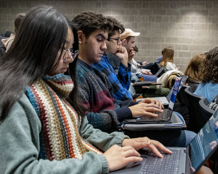 Students taking notes on their laptops in a course