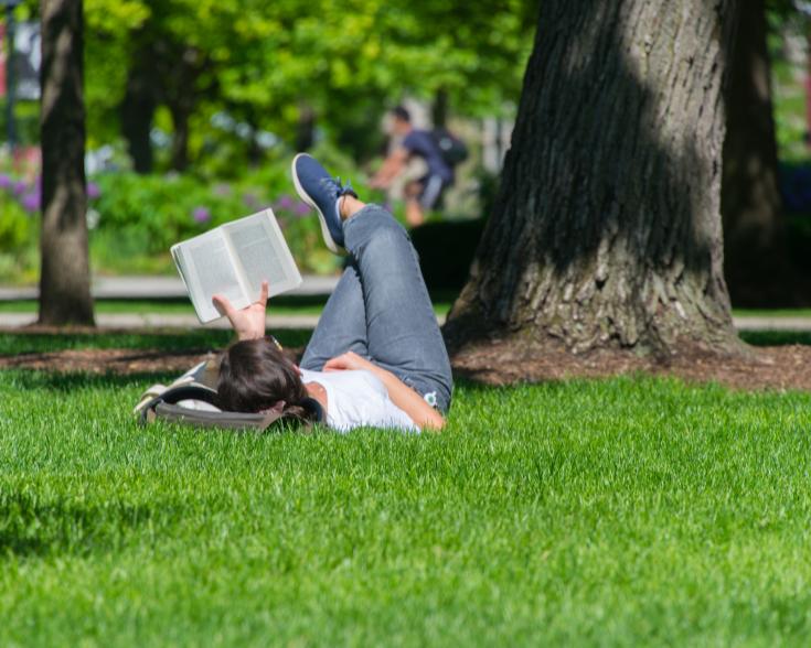 girl laying in the grass on the quad