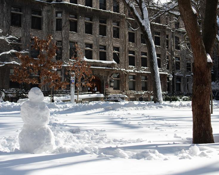 UChicago campus with snow on the ground and a snowman.