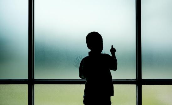 child alone standing at window