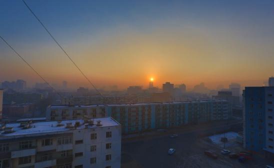 sun rising over hazy cityscape