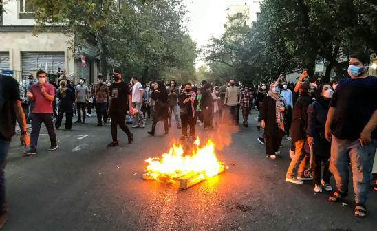 Protestors gather around a fire on the street in Tehran