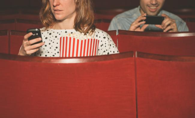 moviegoers on their phones in a theater