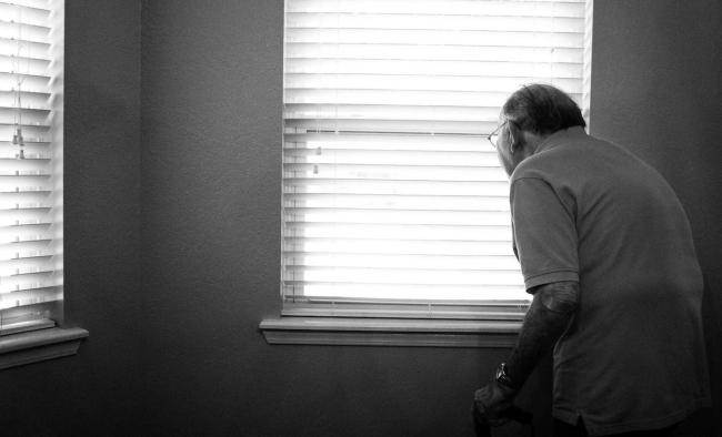 an elderly man looking out of a window