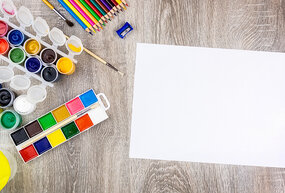 Paint and pencils on a table with paper