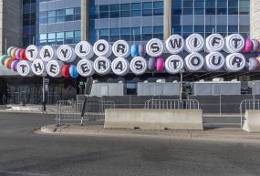 Signage on front of stadium that says "Taylor Swift, The Eras Tour" in friendship bracelet lettering