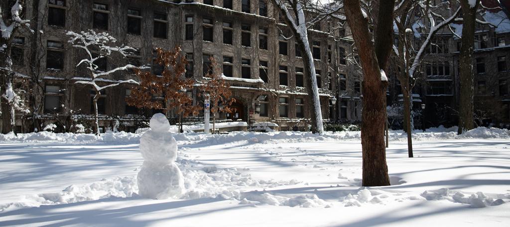 UChicago campus with snow on the ground and a snowman.