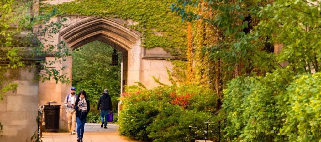 Students walking under arch and garden